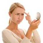 Woman looking at frown lines in mirror